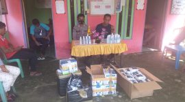 Kepala Desa Linggua Joni Bubane didampingi Bhabinkamtibmas saat menyalurkan Masker dan Handsanitizer kepada Warga setempat