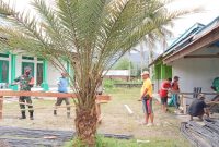 Tampak Babinsa Desa Sidodadi Serda Hadi Suprapto saat membantu warga setempat memotong besi pembangunan Masjid Nurul Hidayah
